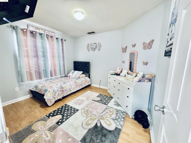 bedroom with a textured ceiling and light hardwood / wood-style flooring