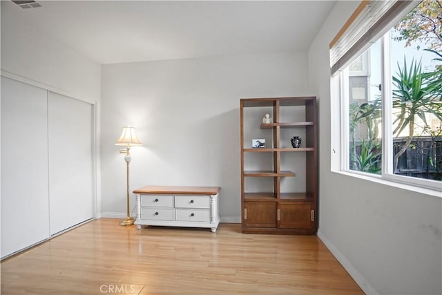 unfurnished bedroom featuring light hardwood / wood-style floors, multiple windows, and a closet