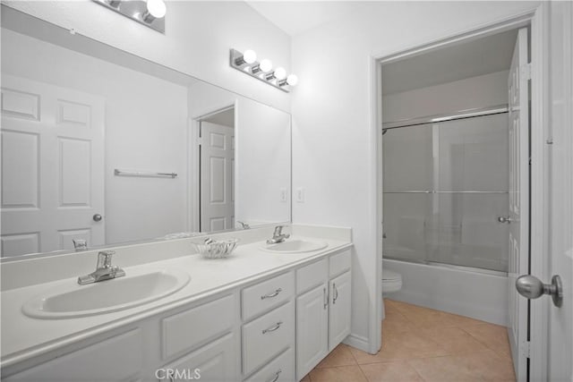 full bathroom with bath / shower combo with glass door, toilet, vanity, and tile patterned flooring