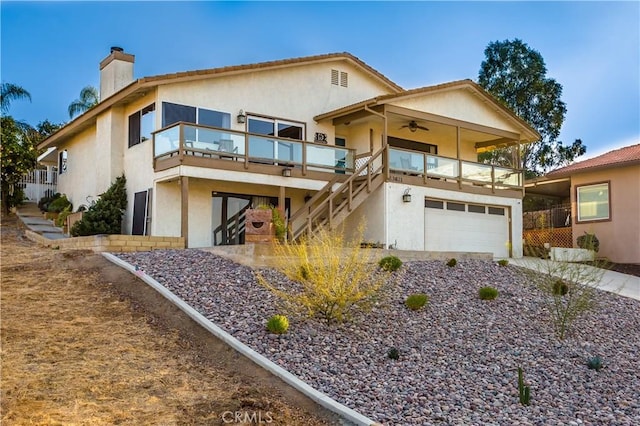 view of front of home with a garage, a balcony, and ceiling fan