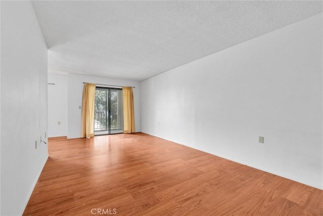 spare room with a textured ceiling and light hardwood / wood-style flooring