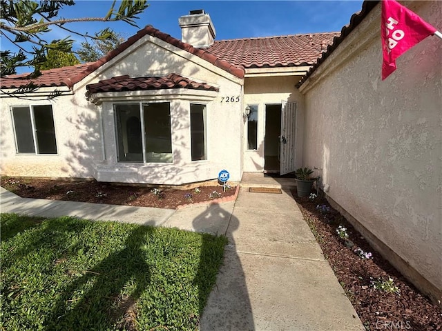 7265 Fletcher View Dr, Highland, CA 92346 - doorway to property with a chimney, a tiled roof, and stucco siding