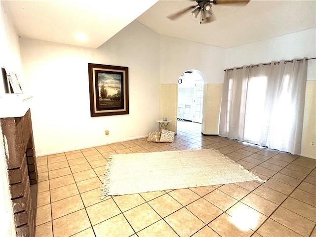 unfurnished living room with arched walkways, light tile patterned floors, vaulted ceiling, and ceiling fan