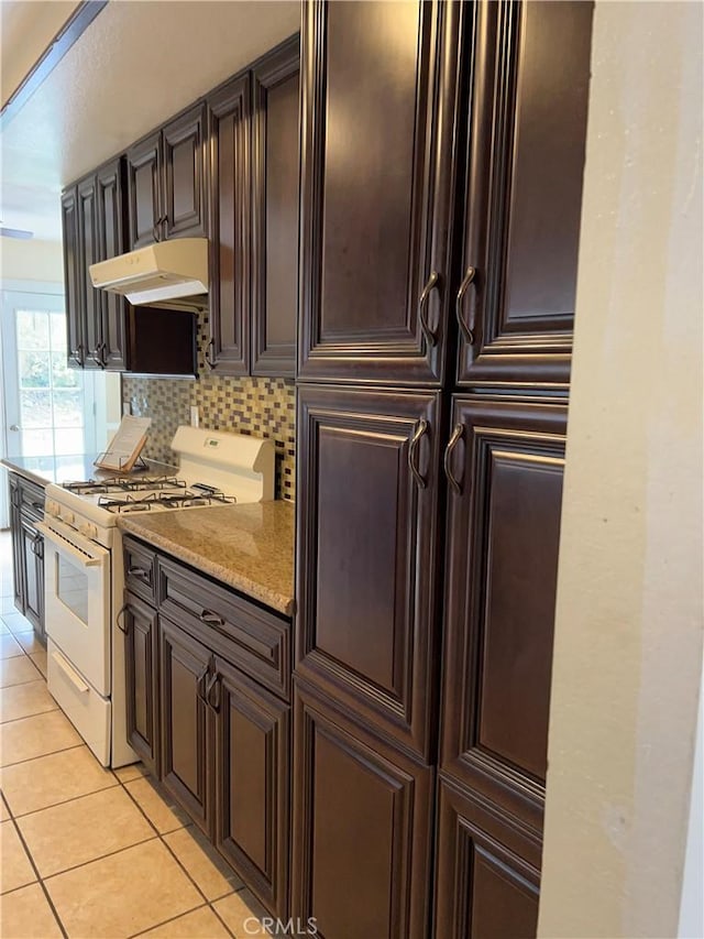 7265 Fletcher View Dr, Highland, CA 92346 - kitchen featuring white range with gas stovetop, under cabinet range hood, light tile patterned floors, decorative backsplash, and dark brown cabinets