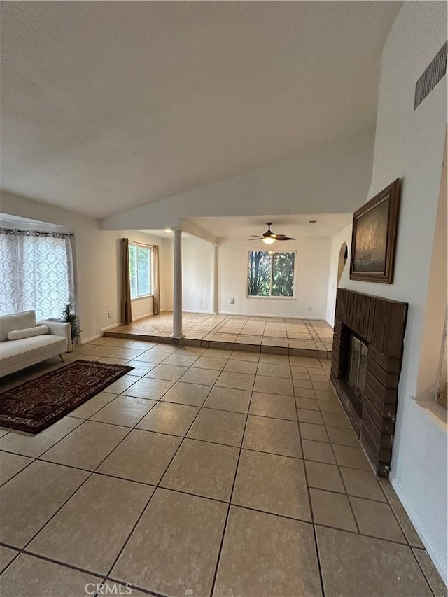 7265 Fletcher View Dr, Highland, CA 92346 - unfurnished living room with tile patterned flooring, a fireplace, a ceiling fan, decorative columns, and vaulted ceiling