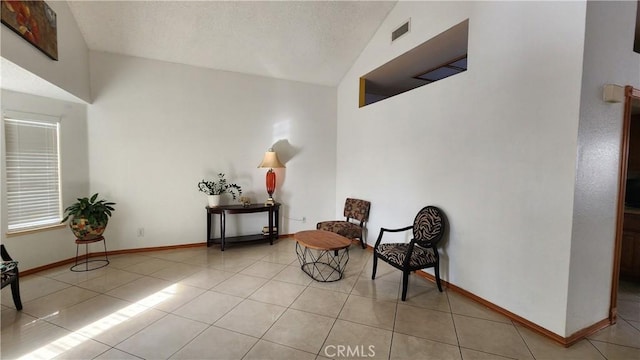 sitting room with light tile patterned floors and vaulted ceiling