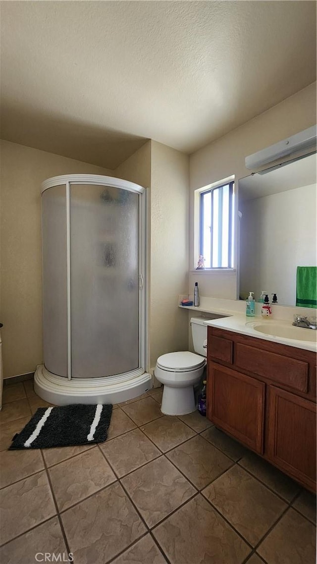 bathroom featuring a shower with shower door, toilet, vanity, and tile patterned flooring