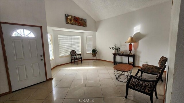 foyer entrance featuring vaulted ceiling, light tile patterned flooring, and a textured ceiling