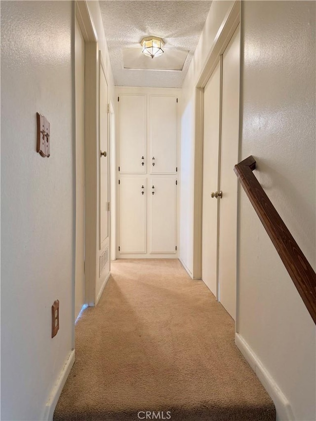 hall with light carpet and a textured ceiling