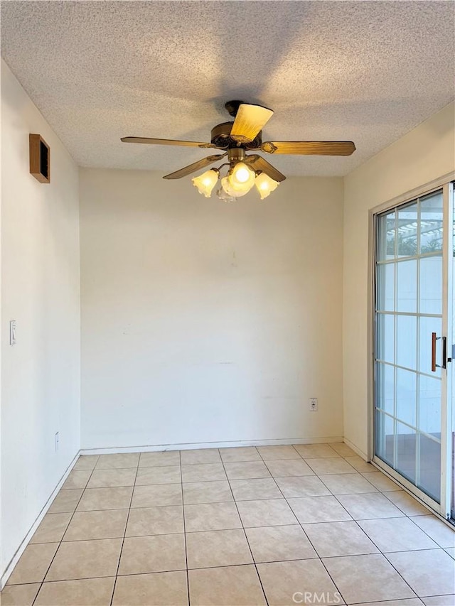 spare room featuring ceiling fan, a textured ceiling, and light tile patterned floors