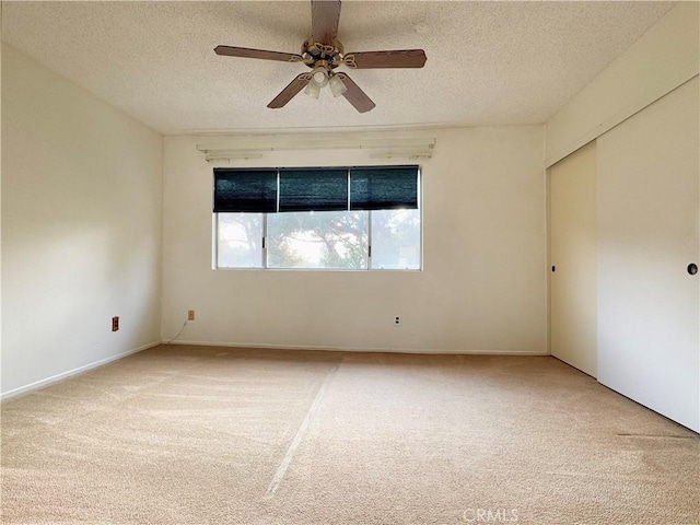 carpeted empty room featuring ceiling fan and a textured ceiling