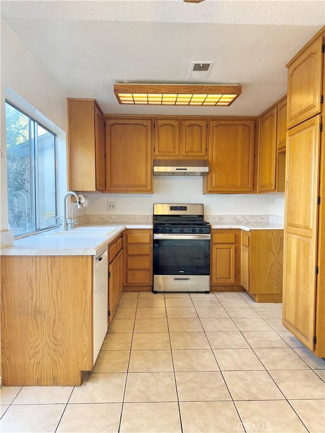 kitchen with dishwasher, light tile patterned floors, stainless steel gas range oven, and sink