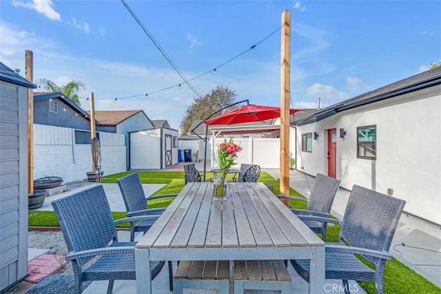 view of patio / terrace featuring a storage shed, outdoor dining space, an outdoor structure, and a fenced backyard