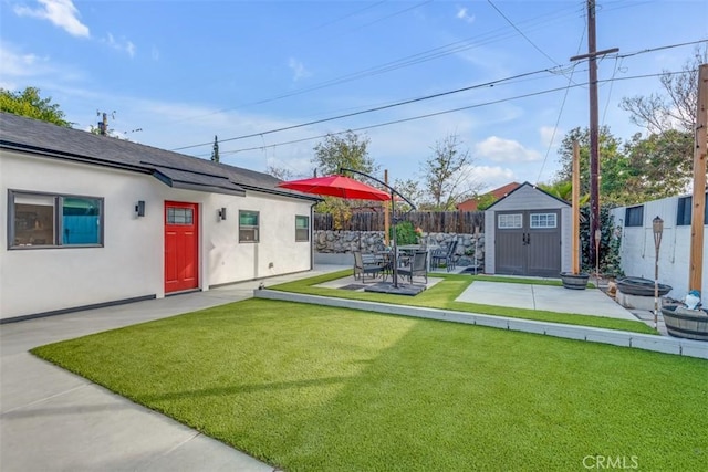 view of yard featuring a patio, a storage unit, an outdoor structure, and a fenced backyard