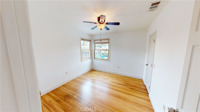 unfurnished room with light wood-style floors, visible vents, baseboards, and a ceiling fan