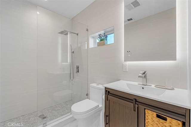 bathroom featuring a tile shower, tile walls, toilet, and vanity