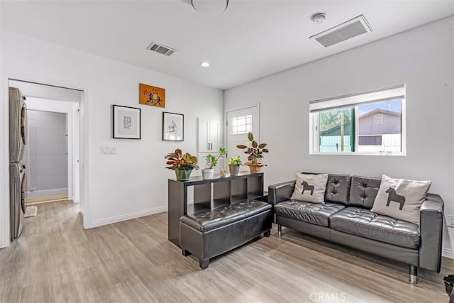 living room featuring light wood finished floors, baseboards, visible vents, and recessed lighting