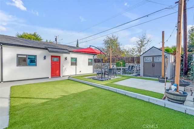 view of yard featuring an outbuilding, a patio, a storage unit, and fence