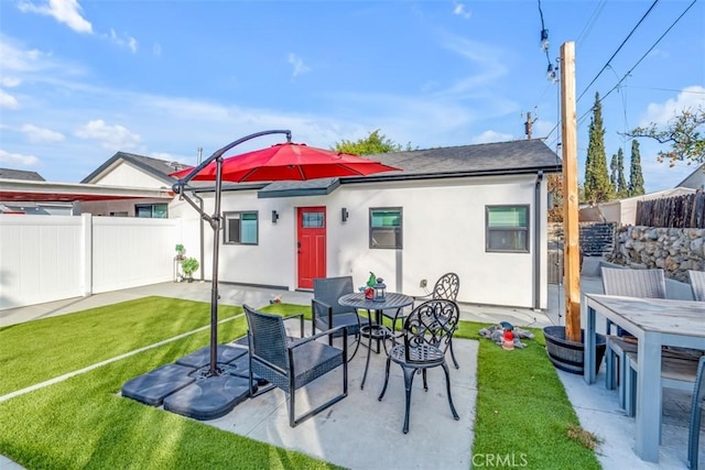 rear view of house with a patio area, fence, stucco siding, and outdoor dining space