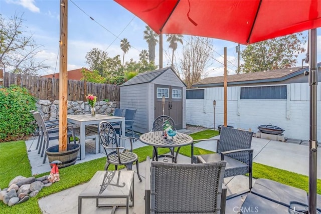 view of patio / terrace featuring a shed, an outbuilding, a fenced backyard, and outdoor dining space