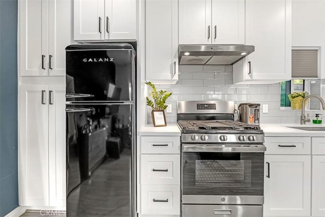 kitchen featuring light countertops, gas stove, freestanding refrigerator, a sink, and under cabinet range hood