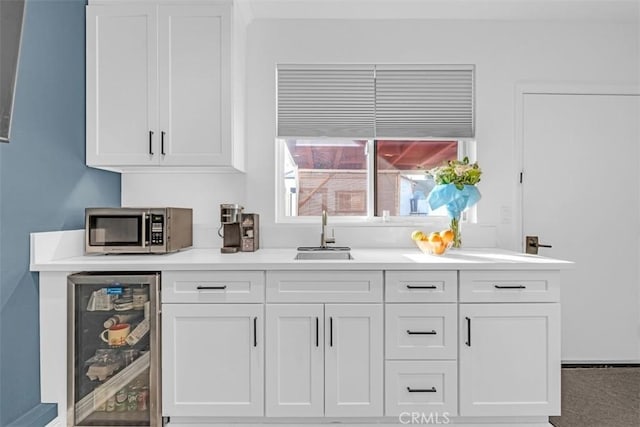 bar featuring beverage cooler, stainless steel microwave, and a sink