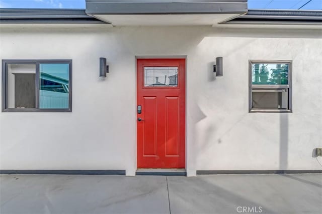 view of exterior entry with solar panels and stucco siding