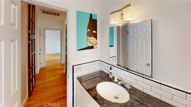 bathroom featuring vanity, tasteful backsplash, wood finished floors, and visible vents