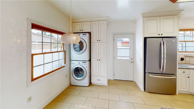 laundry area with laundry area, plenty of natural light, baseboards, and stacked washer and clothes dryer