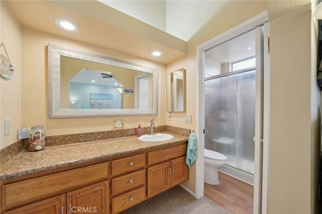 bathroom with vanity, toilet, hardwood / wood-style floors, and a shower with door