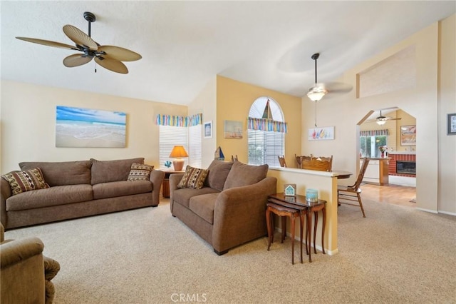 carpeted living room with a fireplace, ceiling fan, and lofted ceiling