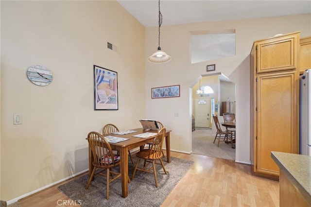 dining room with light hardwood / wood-style flooring and high vaulted ceiling