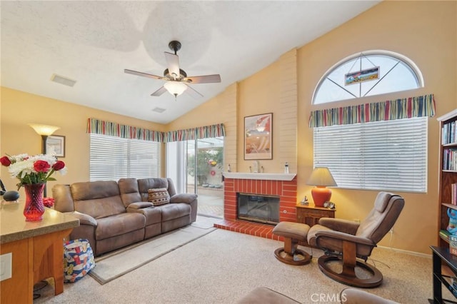 carpeted living room with ceiling fan, a wealth of natural light, vaulted ceiling, and a fireplace