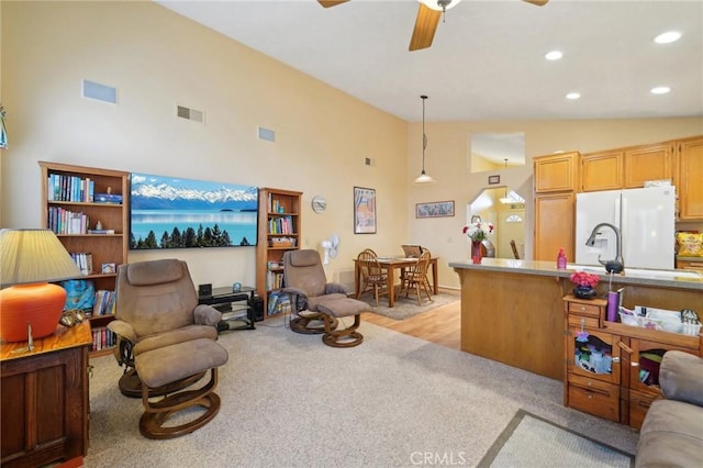 carpeted living room featuring ceiling fan and high vaulted ceiling