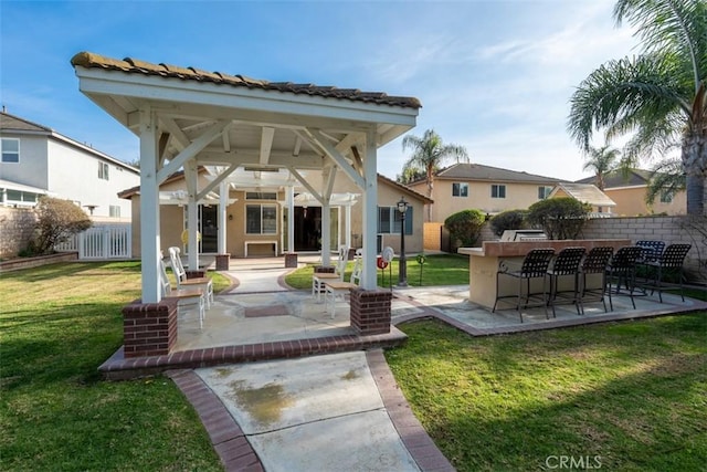 rear view of property with ceiling fan, a patio area, exterior bar, and a lawn