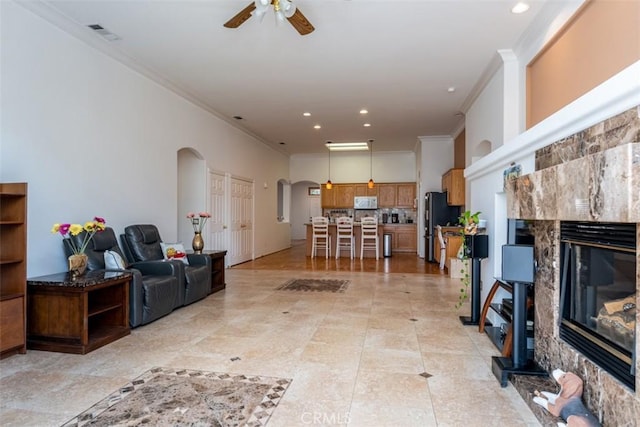 living room featuring ceiling fan, crown molding, and a fireplace