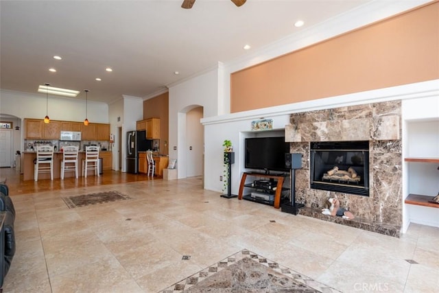 living room featuring ceiling fan, ornamental molding, and a fireplace