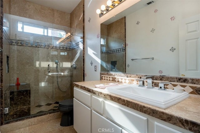 bathroom with tile walls, an enclosed shower, vanity, and toilet