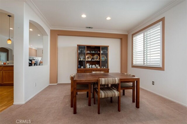 carpeted dining room featuring crown molding