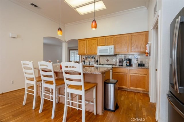 kitchen featuring tasteful backsplash, a center island, pendant lighting, a breakfast bar, and stainless steel fridge