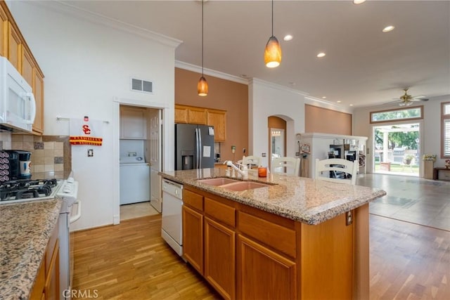 kitchen with ceiling fan, washer / clothes dryer, sink, white appliances, and an island with sink