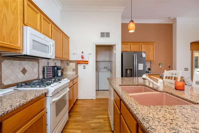 kitchen with tasteful backsplash, decorative light fixtures, white appliances, crown molding, and sink