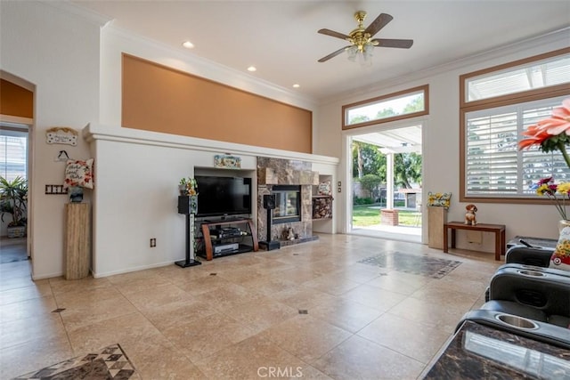 living room with ceiling fan, ornamental molding, a healthy amount of sunlight, and a fireplace