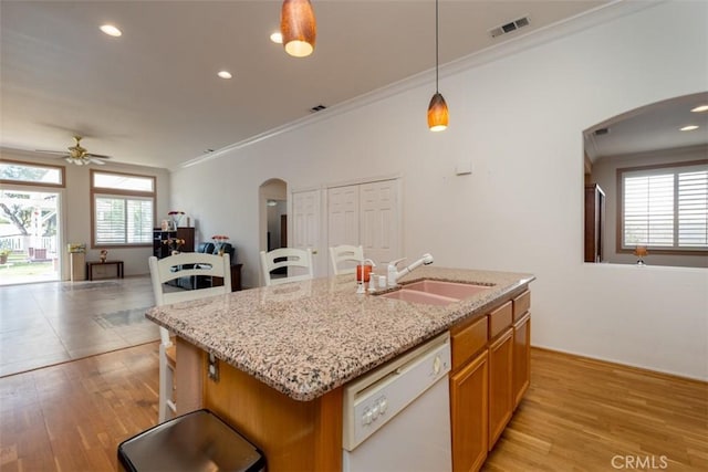 kitchen featuring decorative light fixtures, a center island with sink, sink, crown molding, and white dishwasher