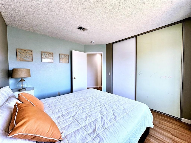 bedroom featuring a textured ceiling, light hardwood / wood-style floors, and a closet