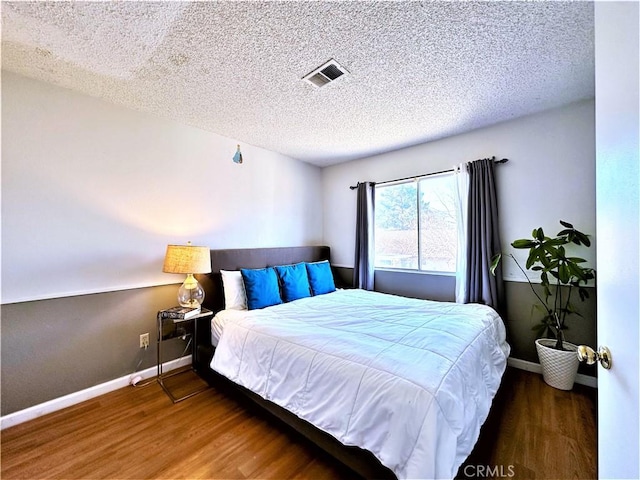 bedroom with a textured ceiling and dark hardwood / wood-style floors