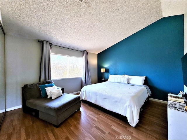 bedroom with a textured ceiling, hardwood / wood-style floors, and vaulted ceiling