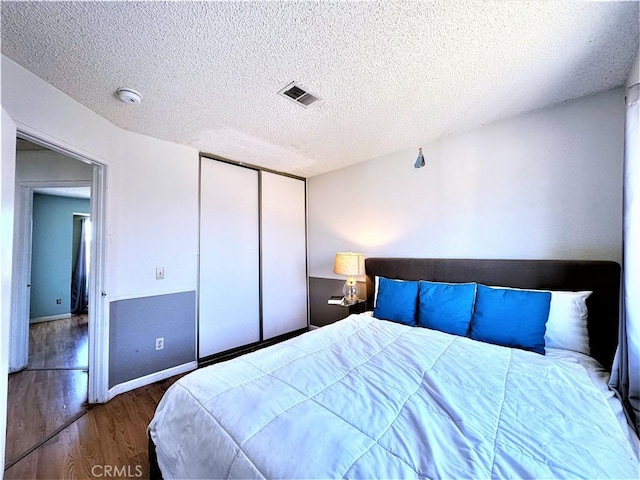 bedroom featuring a textured ceiling, dark wood-type flooring, and a closet