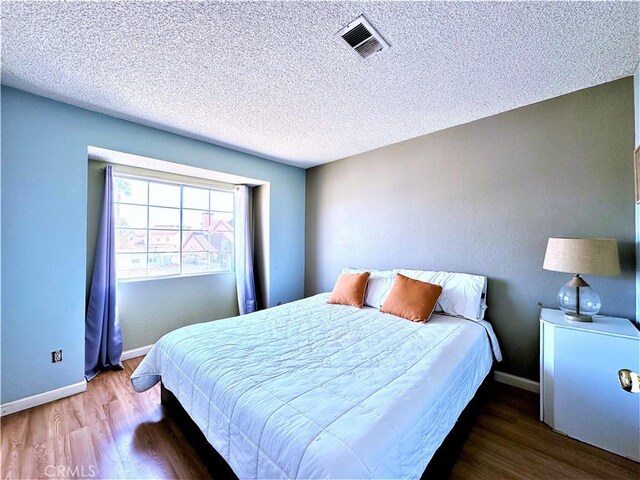 bedroom with hardwood / wood-style flooring and a textured ceiling