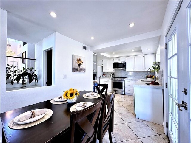 tiled dining area with sink and a raised ceiling